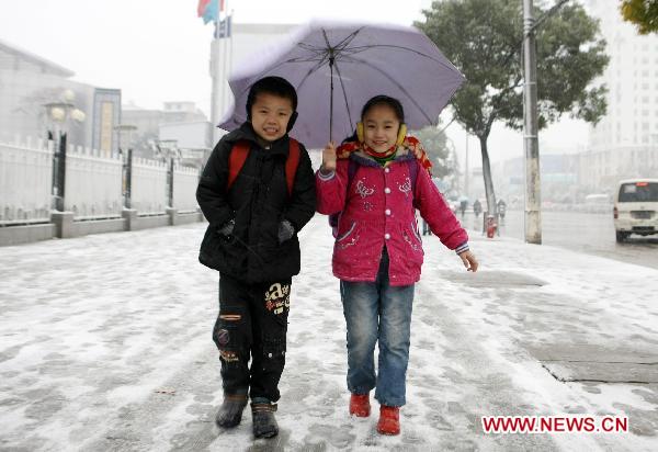Pupils walk on a snow-covered road in Wuhan, capital of central China's Hubei Province, Dec. 15, 2010.