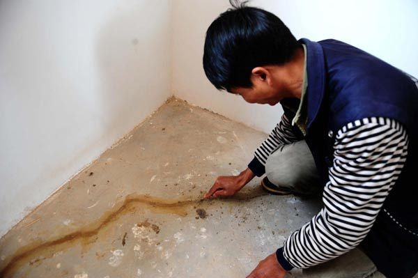 A man clears the crack on the floor at his house in Yao'an, Yunnan Province, Dec 9, 2010. 