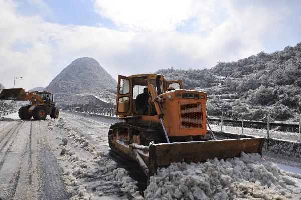 Bulldozers clean the ice and snow on the frozen G4 expressway linking Beijing, Hong Kong and Macao in the section within south China&apos;s Guangdong Province, Dec. 16, 2010. 