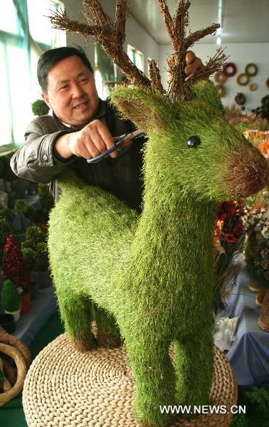 A craftsman trims a reindeer made from grass in Linyi of east China's Shandong Province, Dec. 18, 2010. 