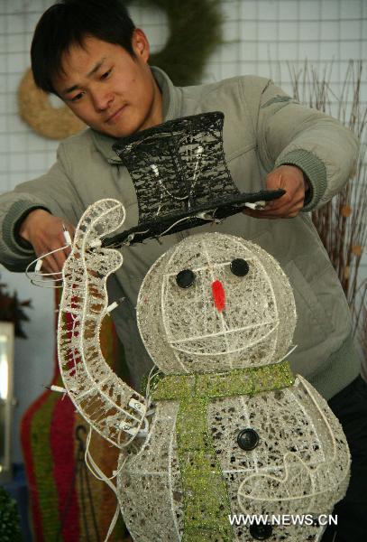 A craftsman trims a snowman made from iron wires in Linyi of east China's Shandong Province, Dec. 18, 2010. 