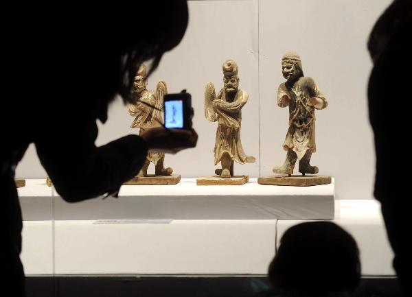 A visitor takes pictures of sculptures of dancing artists that dates back to Tang Dynasty (618-907 A.D.) at the exhibition hall in the National Center For the Performing Arts in Beijing, capital of China, Dec. 20, 2010. 