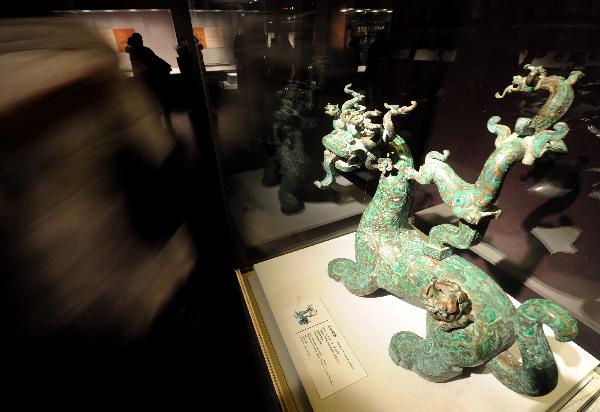 A visitor walks past a bronze sculpture of the Spring and Autumn Period (770 B.C.-476 B.C.) at the exhibition hall in the National Center For the Performing Arts in Beijing, capital of China, Dec. 20, 2010. 