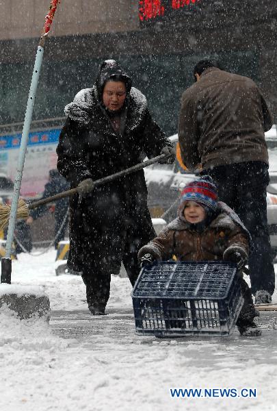 A child helps her grandmother to clear snow covering on the ground in Urumqi, capital of northwest China&apos;s Xinjiang Uygur Autonomous Region, Dec. 21, 2010. 