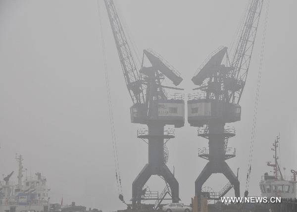 Cranes are seen in fog-shrouded Dalian, northeast China's Liaoning Province, Dec. 22, 2010. Heavy fog hit Dalian Wednesday morning, disrupting the traffic in the coast city as visibility was reduced to less than 50 meters. 