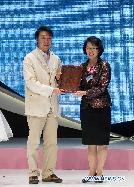Chinese painter Liu Zhong (L) is awarded the ambassador of Water Cellar for Mothers project during a promotion event for the Water Cellar for Mothers in Hong Kong, south China, Dec. 22, 2010.