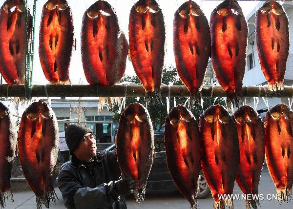 An aquiculture farmer airs fish in Zhuji City of east China's Zhejiang Province, Dec. 26, 2010. 