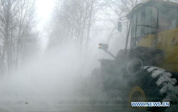 Workers clean the snow blocking the express way connecting Yilan and Boli in northeast China's Heilongjiang Province, Dec. 25, 2010.