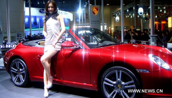 A model promotes a Porsche at the 8th China Guangzhou International Automobile Exhibition in Guangzhou, capital of south China's Guangdong Province, Dec. 27, 2010.