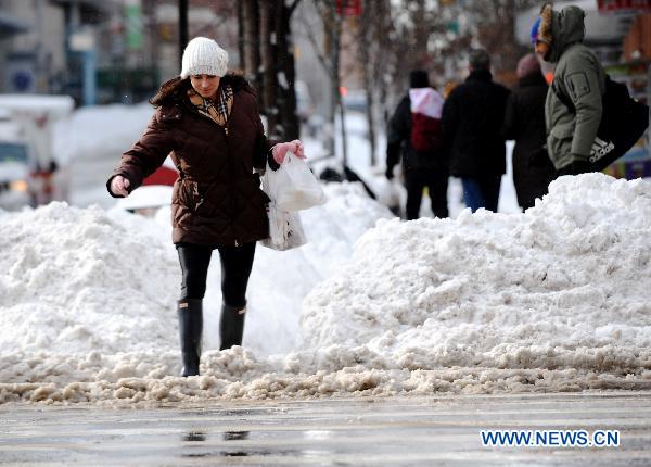 A woman jumps across the snow mound in Manhattan of New York, the United States, Dec. 27, 2010.