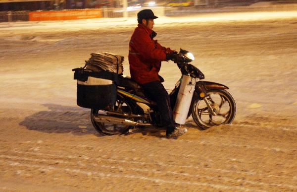 A man rides on the snow covered street in Urumqi, northwest China's Xinjiang Uygur Autonomous Region, Dec. 28, 2010. 