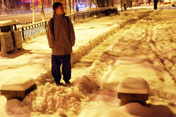 A pedestrian walks on the snow covered sidewalk in Urumqi, northwest China's Xinjiang Uygur Autonomous Region, Dec. 28, 2010.