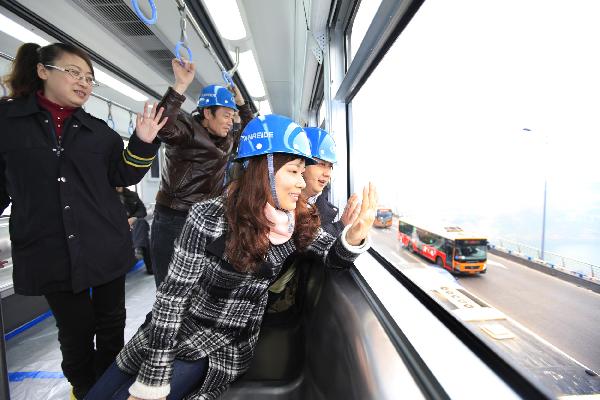 People wave hands on a trial train of Chongqing Subway Line No.3 in southwest China's Chongqing Municipality, Dec. 28, 2010. 