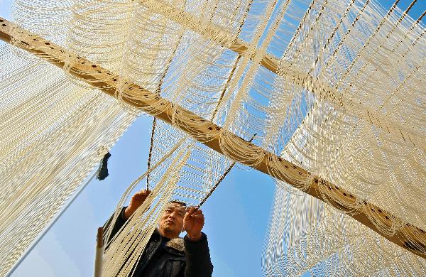 A man dries handmade noodles in Majian Township of Zhuji City, east China's Zhejiang Province, Dec. 30, 2010.