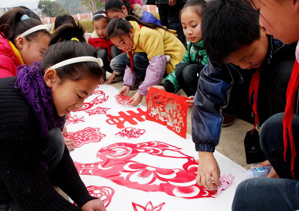 Students show their paper-cutting works during a traditional Chinese paper cutting activity for the upcoming new year in Dexing, Jiangxi Province, Dec. 30, 2010. Paper-cutting works are usually used to decorate doors and windows. [Xinhua photo]