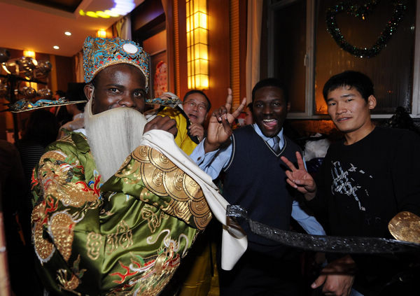 Wearing Peking opera costumes, a student from Togo (L) takes pictures with his friend at the party for Christmas and New Year at Inner Mongolia University of Technology in Hohhot, capital city of north China&apos;s Inner Mongolia Autonomous Region on Dec. 23, 2010. [Xinhua photo] 