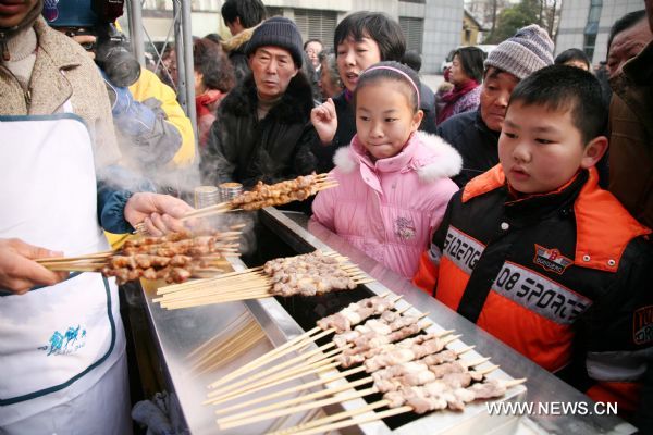 Children wait to eat grilled mutton at a bazar in Nanjing, capital of east China's Jiangsu Province, Jan. 2, 2011.