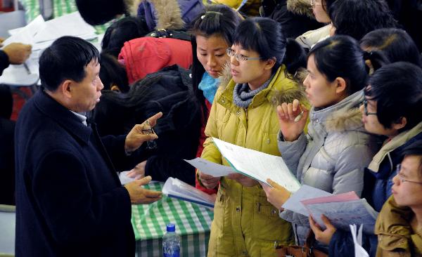 College students talk to a recruiter (1st L) during a job fair in north China's Tianjin Municipality, Jan. 3, 2011. 