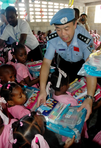 Chinese peacekeeping police distribute crayons and schoolbags to Haitian children.