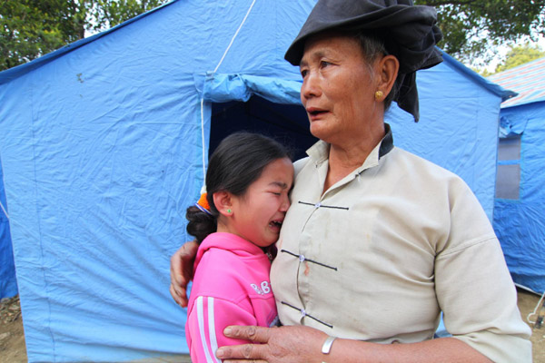 A girl cries on her grandfather&apos;s shoulders in front of their temporary tent in Yingjiang County, Yunnan Province on Jan 3, 2011.