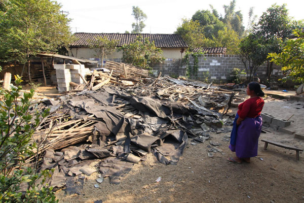 A pregnant woman looks at her damaged house in Yingjiang County, Yunnan Province on Jan 3, 2011.