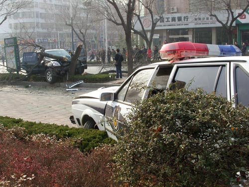 A damaged police car stands meters away from a crashed vehicle shortly after a gunfight in Tai'an, east China's Shandong Province, Jan 4, 2011. 