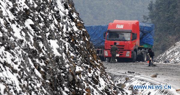 Men deal with an accident after a rollover happened to a vehicle on a highway due to icy roads in Huaihua, central China's Hunan Province, Jan. 3, 2010.