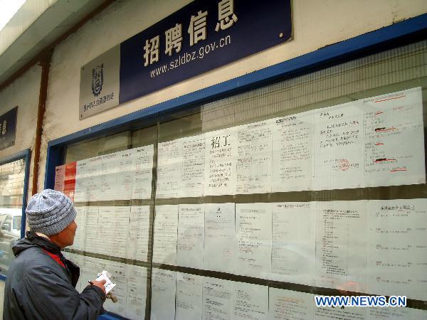 A job hunter reads information during a job fair in a human resource center in Suzhou, east China's Jiangsu Province, Jan. 4, 2011. 