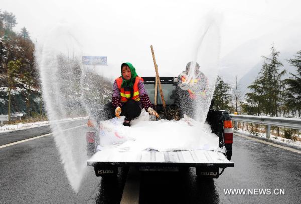 Workers spread salt to help ice thaw on a highway in southwest China&apos;s Chongqing Municipality, Jan. 5, 2011. 