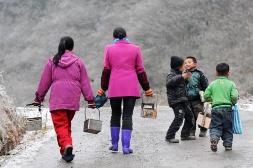 Holding makeshift stoves, students walk on their way home after school on an iced mountain road in Xinhuang Dong Autonomous County in western-most Hunan Province, Jan 6, 2011. 