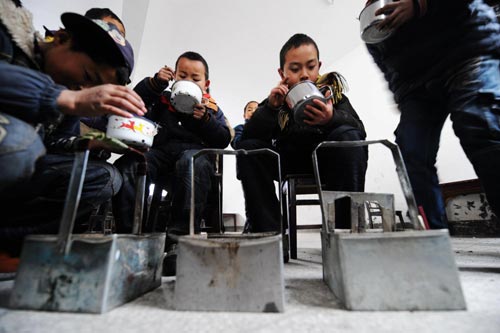 Students dine around their makeshift hand-stoves at a school in Chaping township, Xinhuang Dong Autonomous County in central China's Hunan Province, Jan 6, 2011.