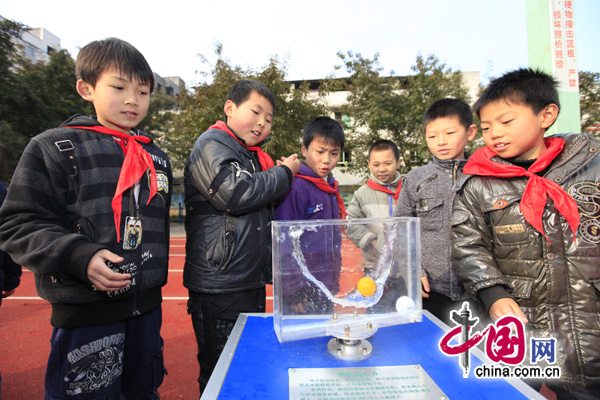 A science exhibit demonstrates the principle of centrifugal force to left-behind children.