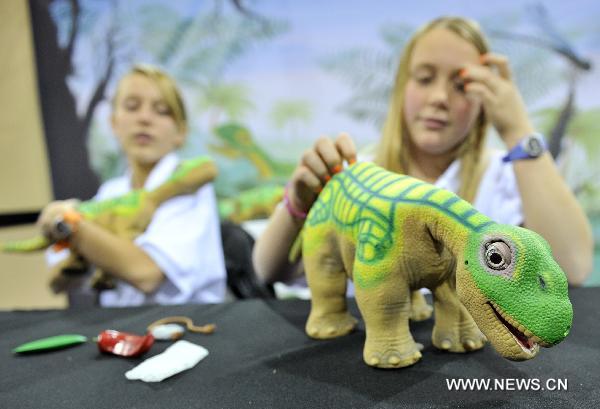 Two girls play with robot dinosaur Pleo during the 2011 International Consumer Electronics Show in Las Vegas, the United States, Jan. 8, 2011.