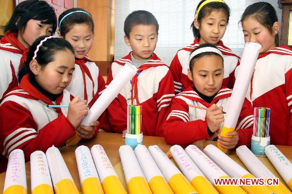Pupils inscribe cautions against smoking on cigarette models made by themselves in Zaozhuang City, east China's Shandong Province, Jan. 7, 2011. 