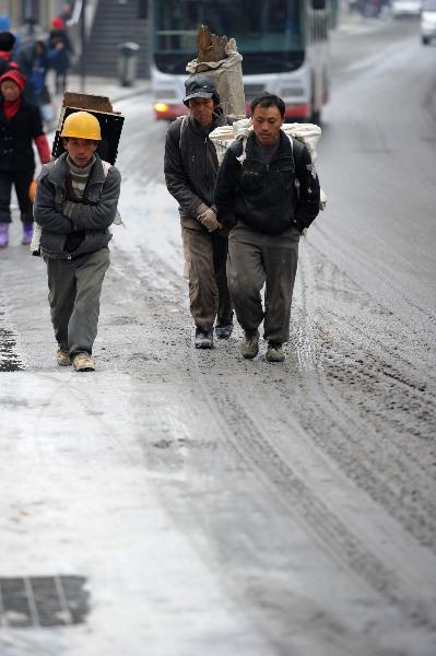 Migrant workers walk on a street coated by ice and snow in Guiyang City, capital of southwest China's Guizhou Province on Jan. 10, 2011.