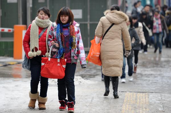 Two girls wearing heavy coats walk in a street of Guiyang City, capital of southwest China's Guizhou Province on Jan. 10, 2011. 