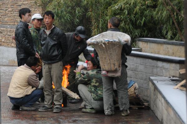 Migrant workers warm themselves by the fire in Guiyang City, capital of southwest China's Guizhou Province on Jan. 10, 2011.