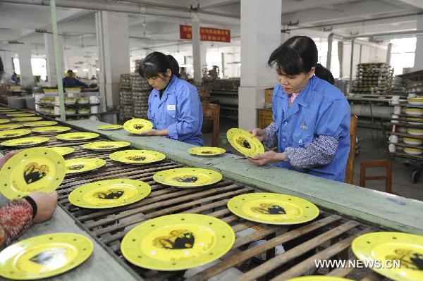 Workers work on product line of chinaware at a workshop of Tri-Ring Group Corporation in Beiliu City, south China's Guangxi Zhuang Autonomous Region, Jan. 10, 2011.