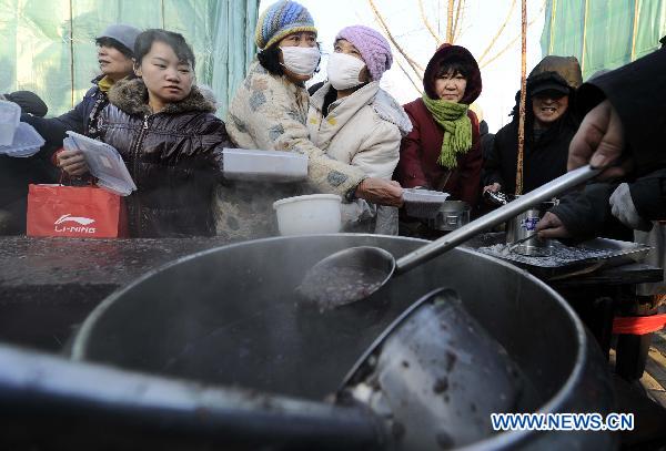 People queue up to have a taste of Laba Porridge, a special food cooked with fresh paddy rice, dried fruits and nuts, in Guanyin Temple, north China's Tianjin Municipality, Jan. 11, 2011. 
