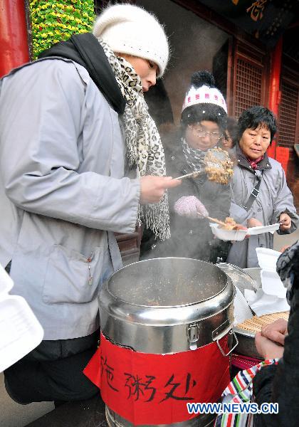 A man from Baiyun Temple distributes Laba porridge to people in Taiyuan, north China's Shanxi Province, Jan. 11, 2011.