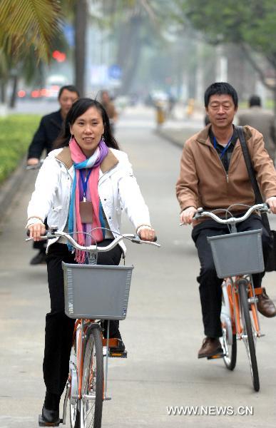 Local residents ride public bicycles in Haikou, capital of south China's Hainan Province, Jan. 11, 2011. 