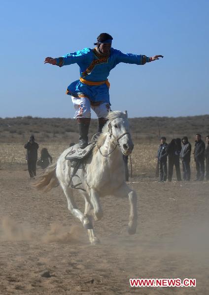 A man demonstrates stunt skills on a horse back during a horse racing competition in Etogqian Qi, north China's Inner Mongolian Autonomous Region, Jan. 12, 2011.