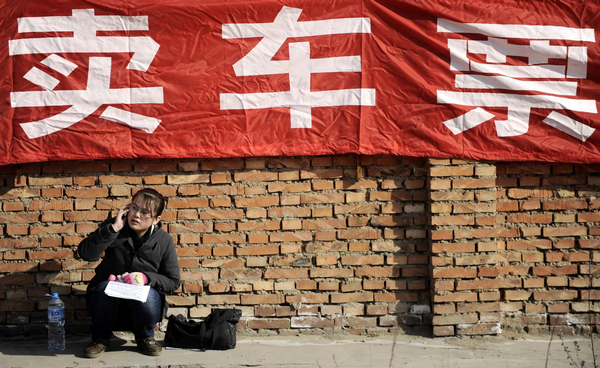 A woman talks on a phone while sitting in front of the temporary tickets-selling counters in Tianjin Railway Station, Jan 12,2011.