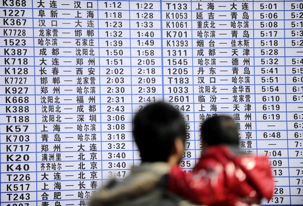 A man holds a baby while checking the newly-released train schedule board at Tianjin railway station, Jan 12, 2011. As Spring Festival approaches, fifteen temporary counters are open to the public to shorten waiting times in Tianjin.