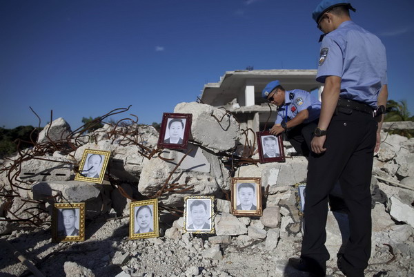 A Chinese peacekeeper places photos of colleagues killed in Haiti earthquake on the debris of the headquarters of United Nations Stabilization Mission in Haiti(MINUSTAH) at a memorial in Port au Prince, Jan 12, 2010.