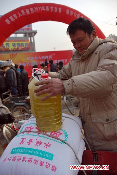Resident Gao Yuge, from a low-income family, is presented daily necessities by local government in Liaocheng City, east China's Shandong Province, Jan. 14, 2011, ahead of Chinese Spring Festival, which falls on Feb. 3 this year.