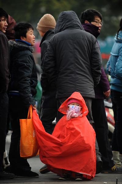 A girl named Wang Xiaoyu (front) and her mother queue to buy tickets at a temporary ticket agency in Ningbo, east China's Zhejiang Province, Jan. 15, 2011. 