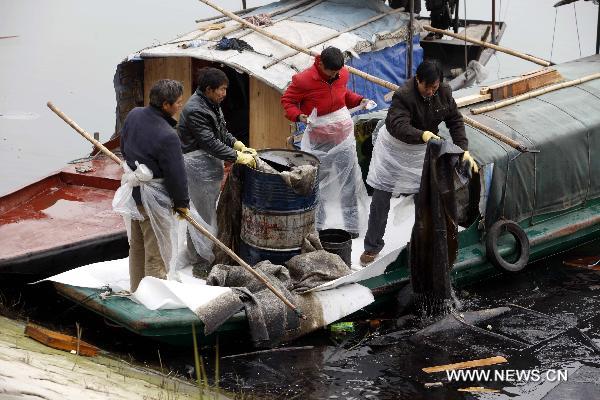 Rescuers clean fuel oil spilling out of a sunken vessel on the reservior of the Three Gorges Dam in Yichang, central China's Hubei Province, Jan. 17, 2011. 