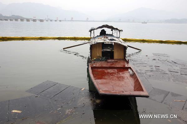 A rescuer rows a boat as he tries to clean fuel oil spilling out of a sunken vessel on the reservior of the Three Gorges Dam in Yichang, central China's Hubei Province, Jan. 17, 2011. 