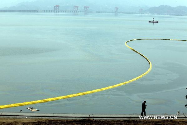 Containment booms are placed to block fuel oil spilling out of a sunken vessel on the reservior of the Three Gorges Dam in Yichang, central China's Hubei Province, Jan. 17, 2011. 